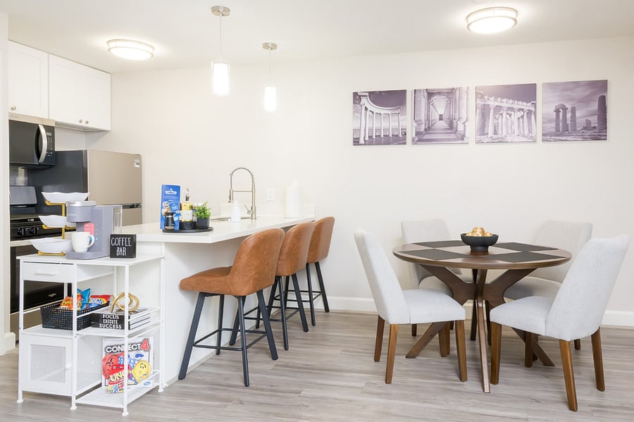 Gather for a meal in this elegant dining area, featuring a round wooden table, stylish upholstered chairs, and a sleek breakfast bar.