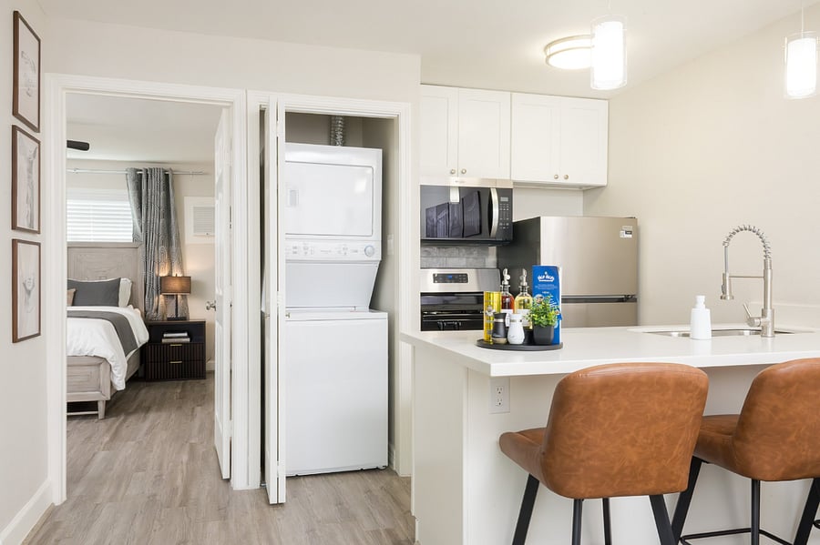 The modern kitchen area features a conveniently integrated laundry closet with a stacked washer and dryer, ensuring a practical and efficient stay.