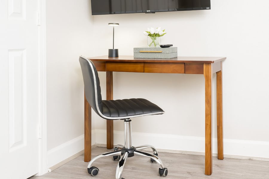 Enjoy a quiet and productive moment at this sleek wooden desk, paired with a comfortable chair for the perfect remote work setup.