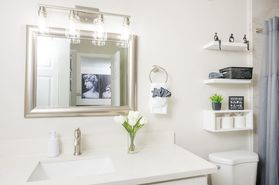Bright and pristine bathroom space, thoughtfully organized with modern floating shelves and elegant silver accents.
