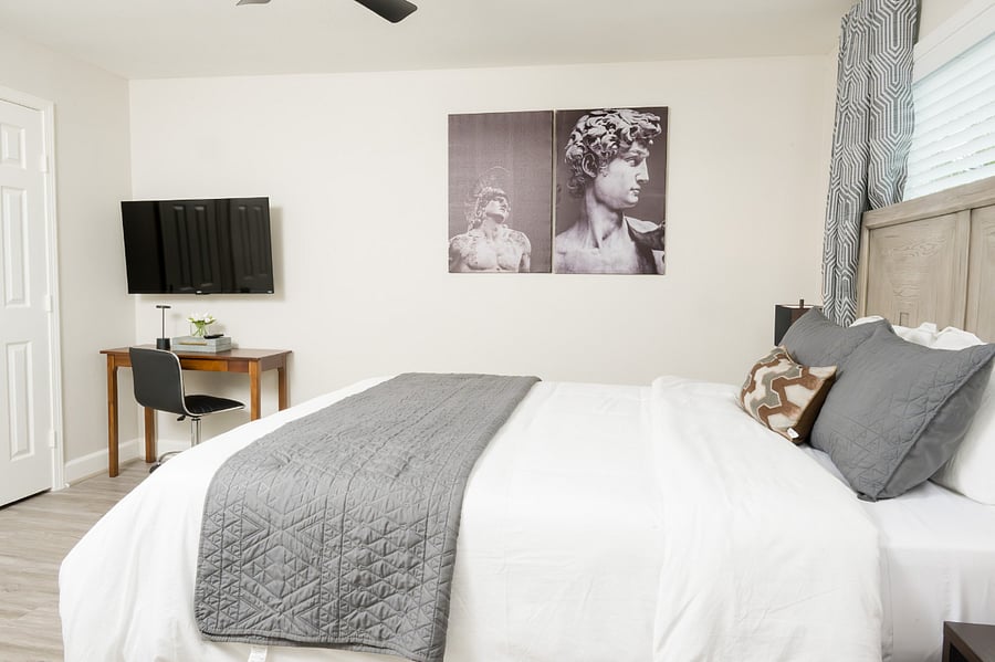Unwind in this chic, modern bedroom featuring a plush king-sized bed and a dedicated workspace for your convenience.