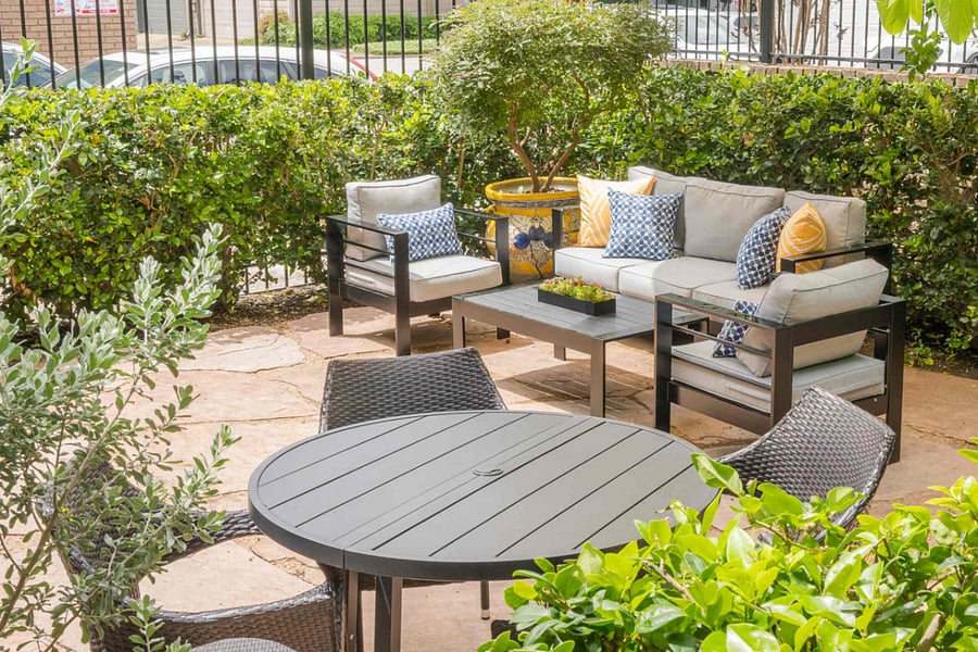 Relax in this enchanting private patio, complete with comfortable lounge seating, an al fresco dining area, and a lush, green atmosphere.