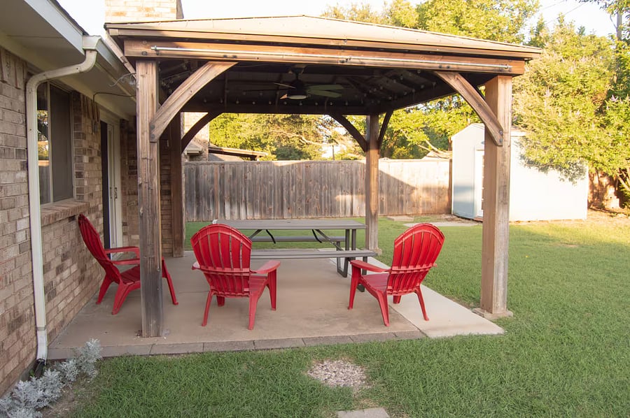 This covered patio includes seating, outdoor fan and patio lights.