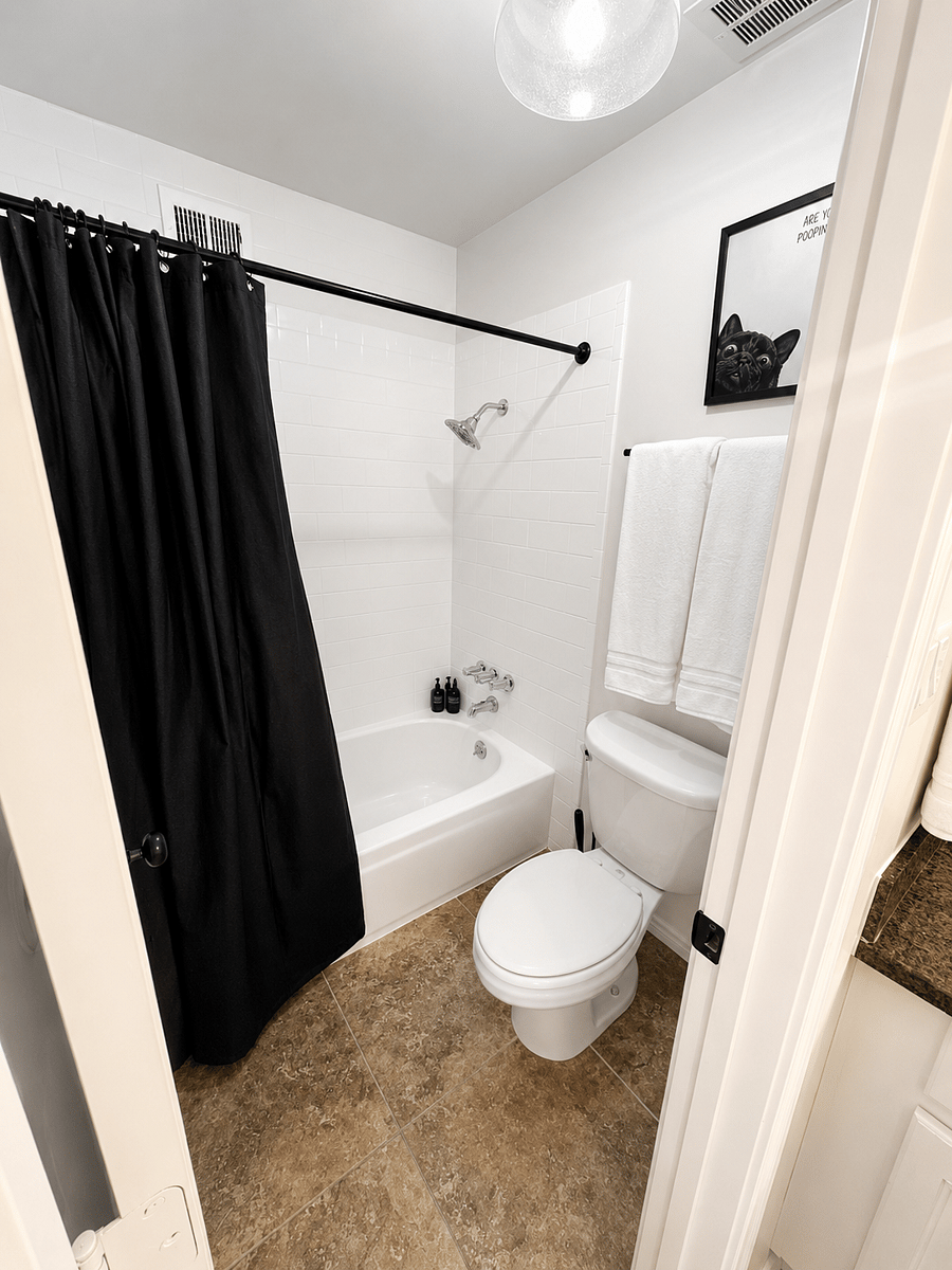 Primary bathroom with granite counters and toilet closet with bathtub-shower.