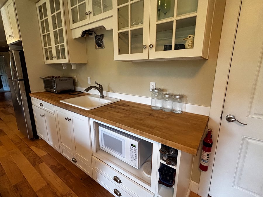 Kitchen with large fridge, microwave, counter oven, well-appointed kitchenware and beautiful stoneware dishes. 
