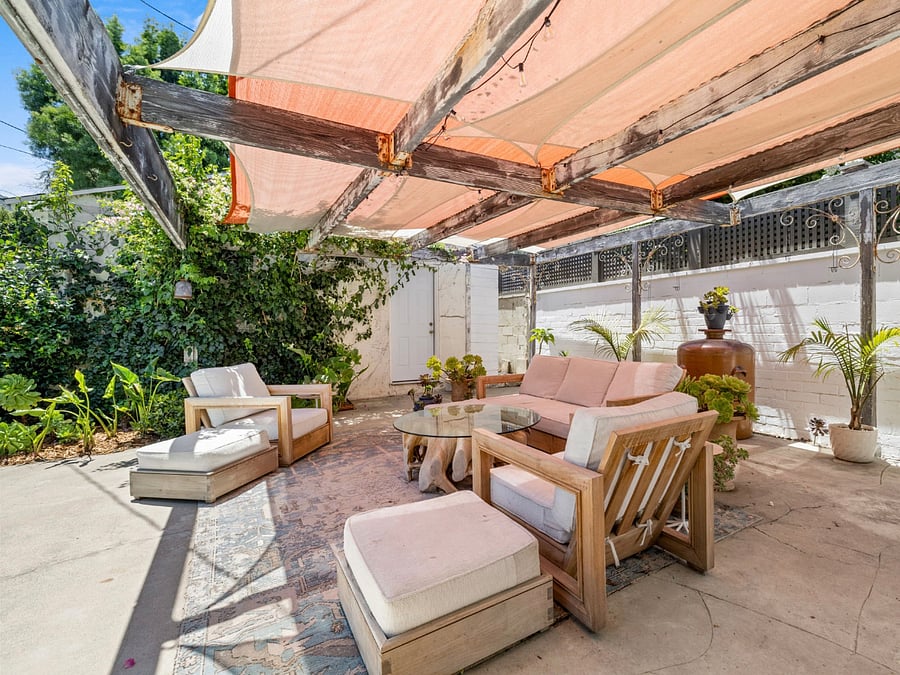 Outdoor living space in fully enclosed garden with fruit trees and shade.