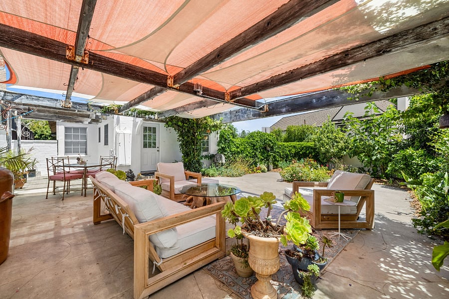 Outdoor living space in fully enclosed garden with fruit trees and shade.