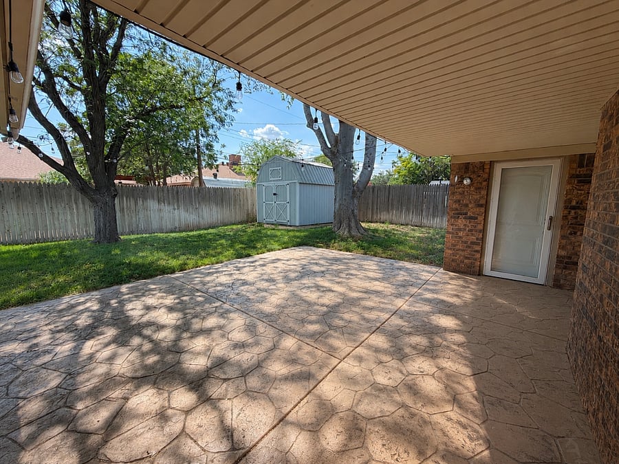 Covered Patio with 2 large trees and storage shed