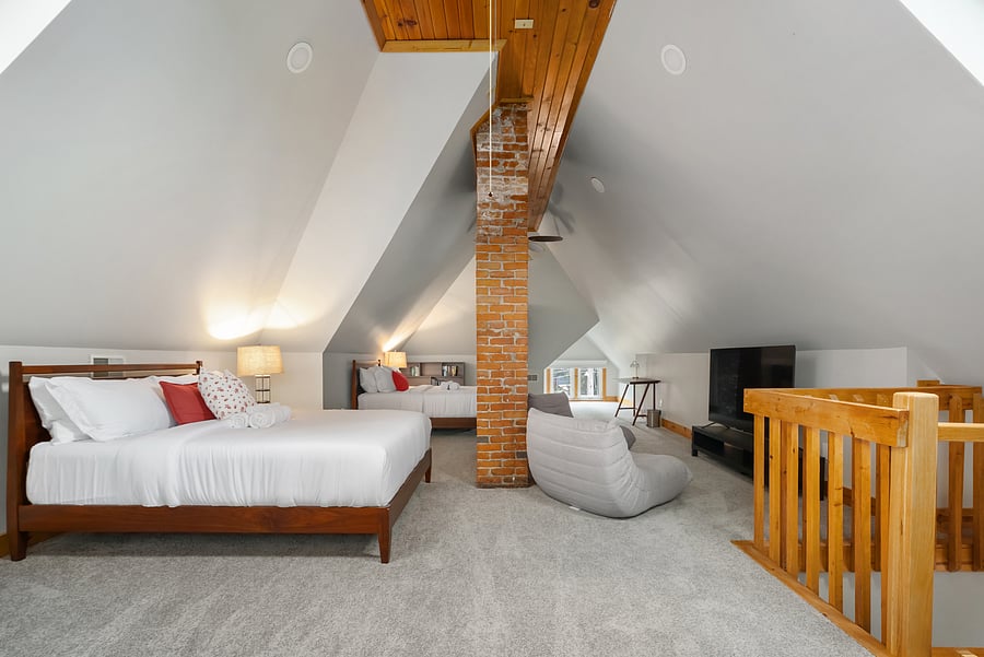 Spacious third floor featuring a bed, lounge seating, and exposed brick