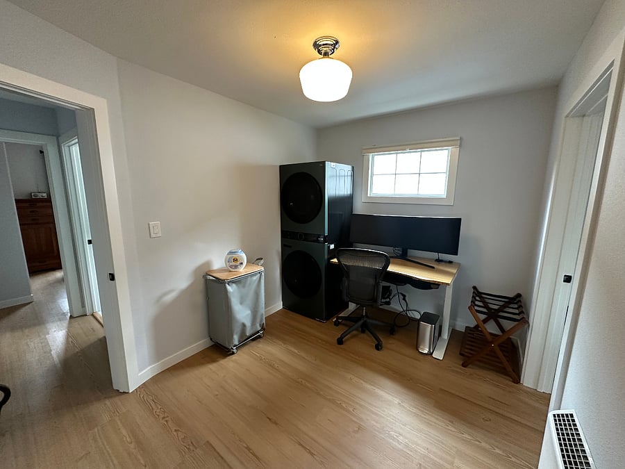 Office and laundry room with sit/stand desk and full-sized washer and dryer.