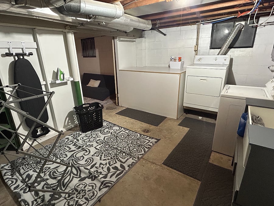 Large, well-lit laundry area in the basement; full size washer and dryer; laundry sink; ironing area; folding table