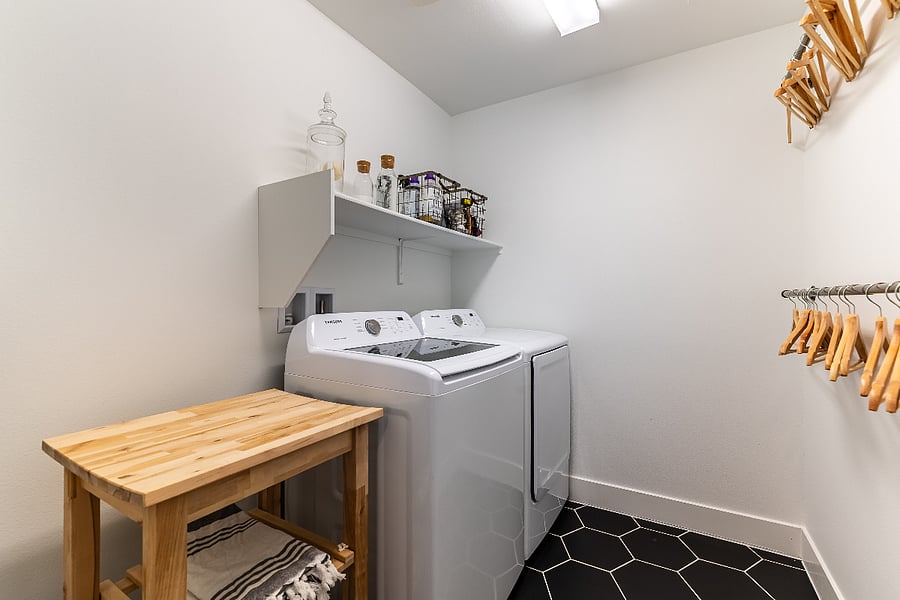 Convenient upstairs laundry room with full-size washer and dryer, storage and folding space.