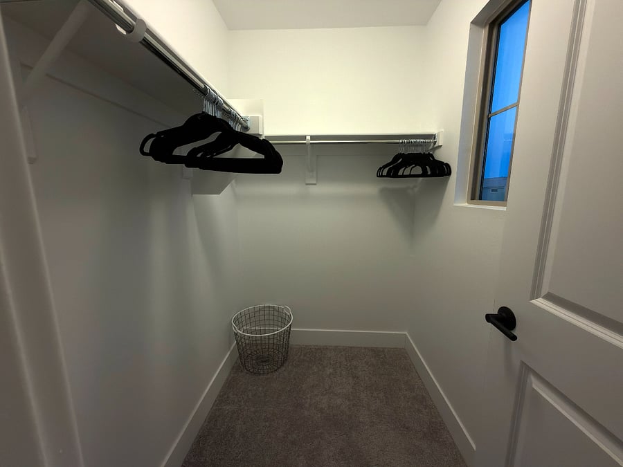 Walk-in closet in the second upstairs bedroom with ample hanging space and natural light.