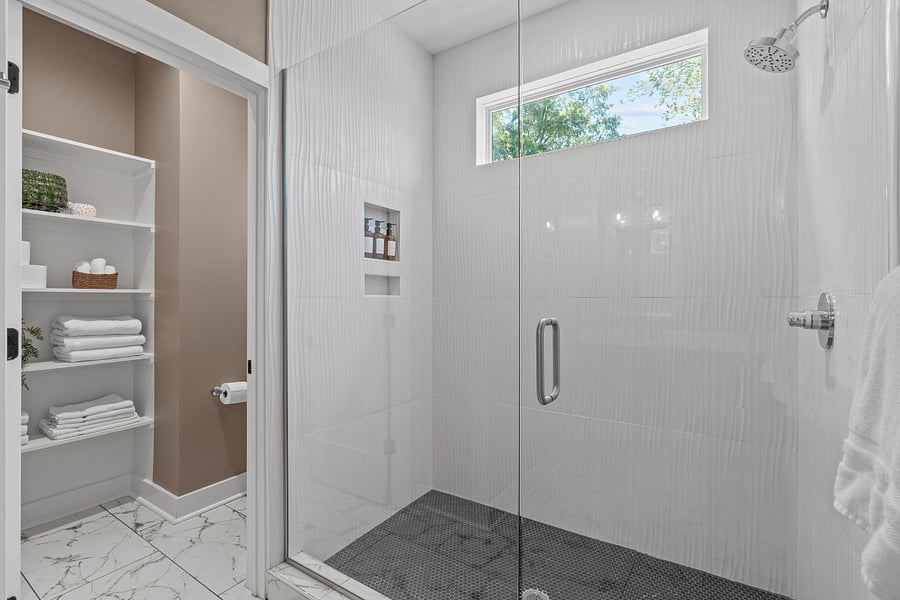 Primary ensuite with custom tiled walk-in shower, glass enclosure & proper water closet.