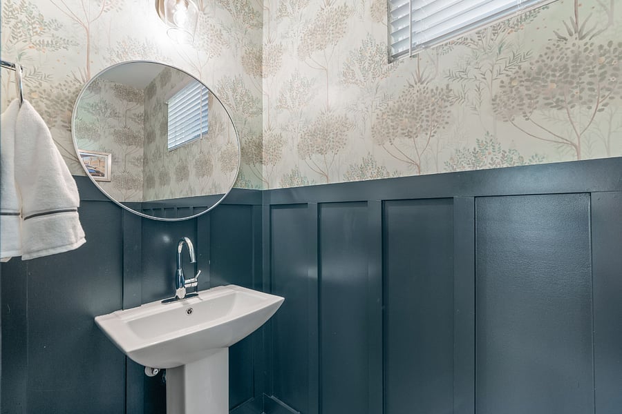 Downstairs powder room decorated with custom wainscoting and designer wallpaper.