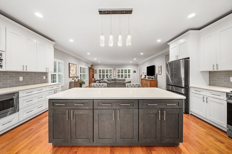 The spacious kitchen features quartz countertops, an expansive dark espresso center island, white shaker cabinetry, a timeless tile backsplash, a new refrigerator (2026), a new slide-in gas range (2026), and an upgraded dishwasher (2024).