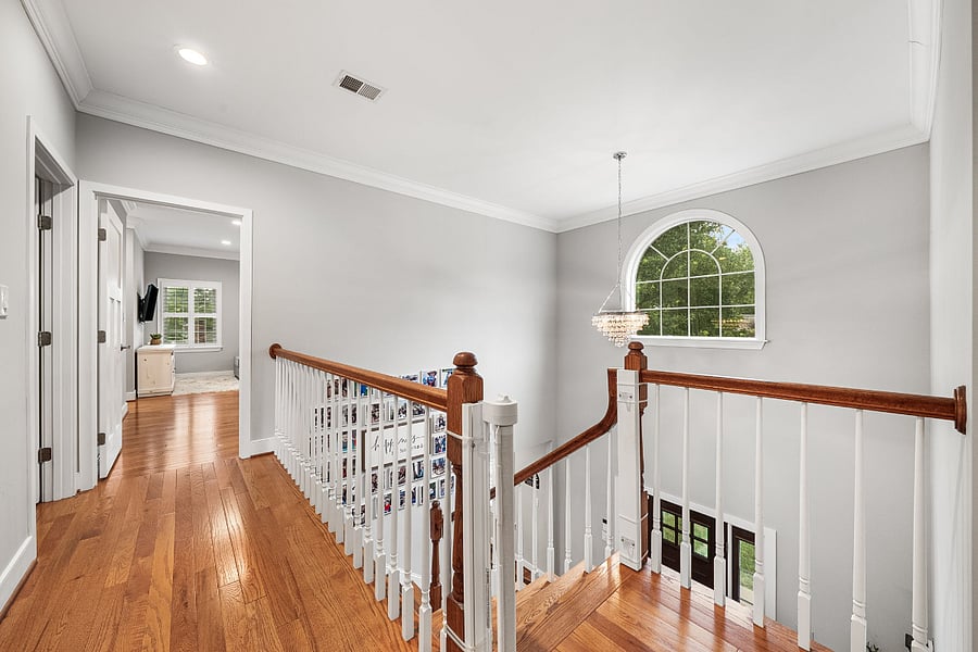 The two-story foyer leads to the second floor up the wooden staircase. Natural hardwood flooring continues throughout the hallway and all four bedrooms.