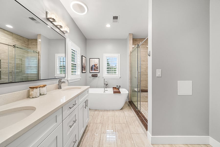 The primary bathroom includes a luxurious bath with a freestanding soaking tub, double vanity, and a stunning floor-to-ceiling frameless glass tile shower.