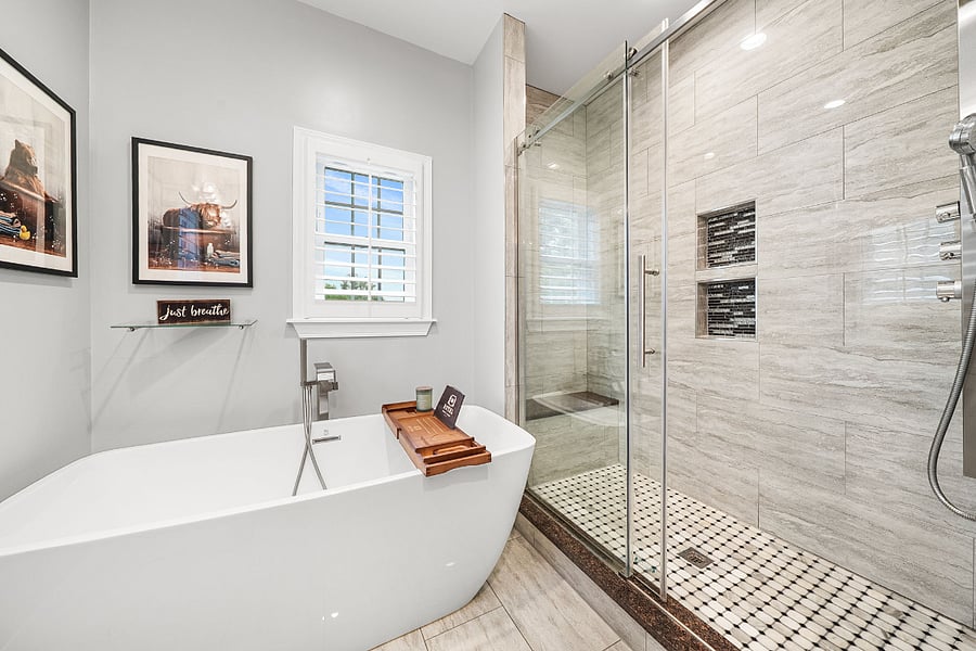 The primary bathroom includes a luxurious bath with a freestanding soaking tub, double vanity, and a stunning floor-to-ceiling frameless glass tile shower.