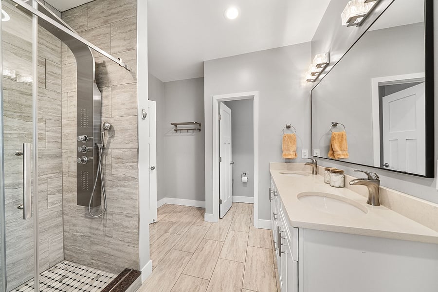 The primary bathroom includes a luxurious bath with a freestanding soaking tub, double vanity, and a stunning floor-to-ceiling frameless glass tile shower.