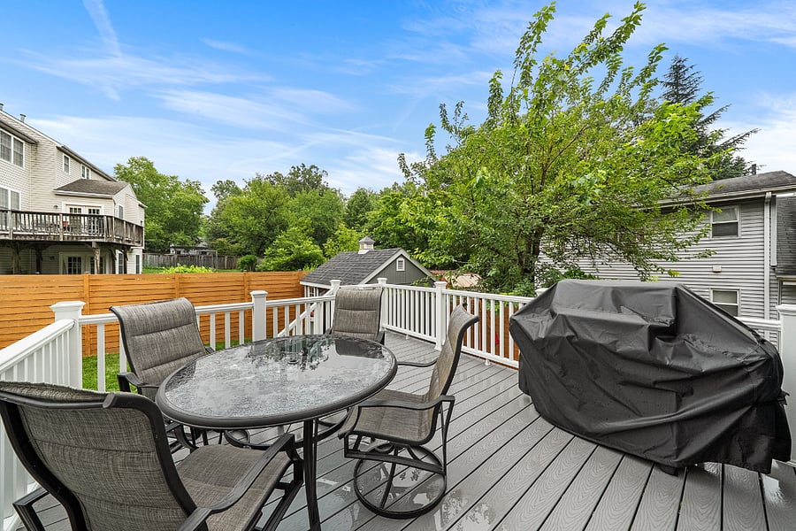 French doors off the kitchen open to a low-maintenance Trex deck with a dining table and grill.