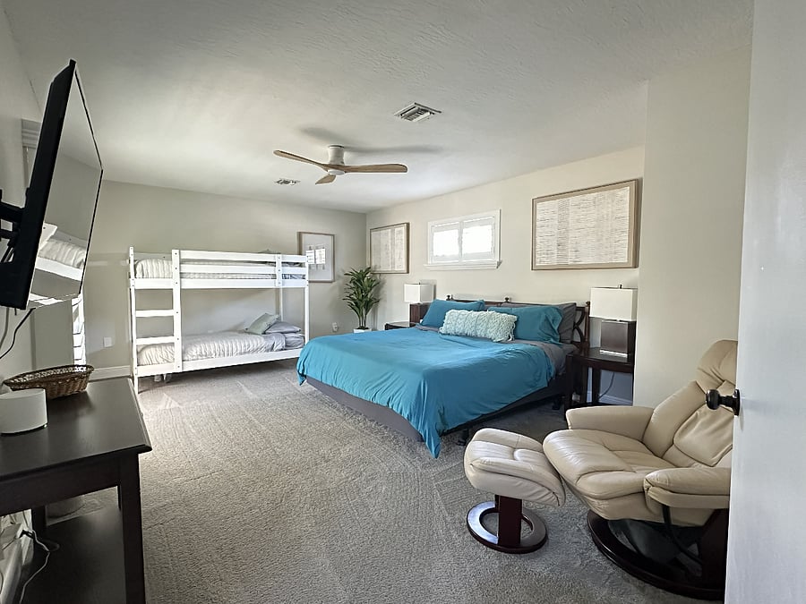 The spacious upstairs master bedroom features a king-sized bed and a set of bunk beds, perfect for flexible sleeping arrangements.