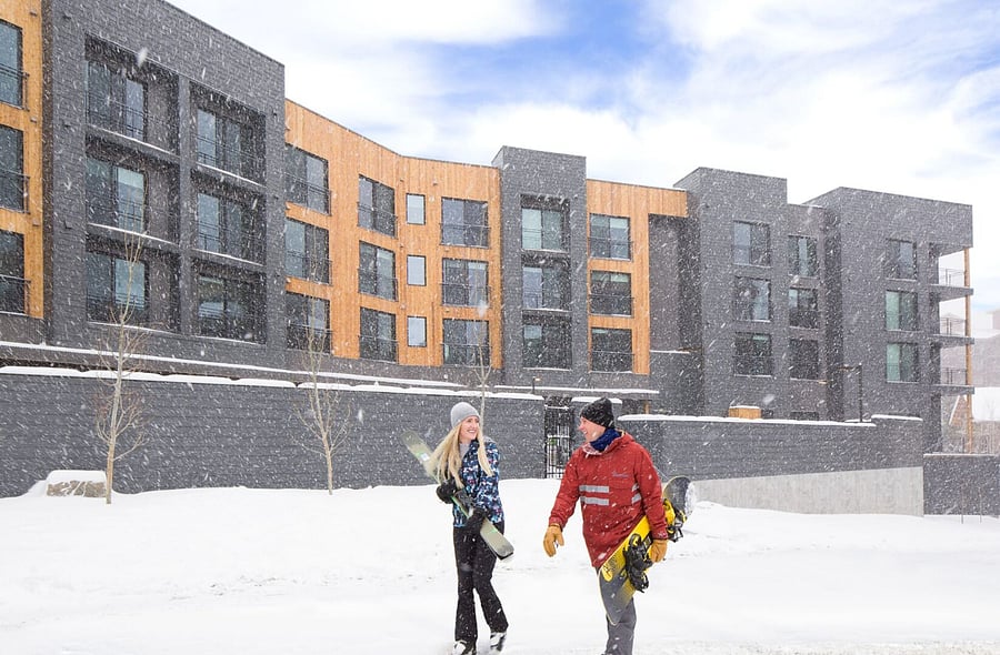 Canyon Haus snowy exterior with couple walking to the lifts.