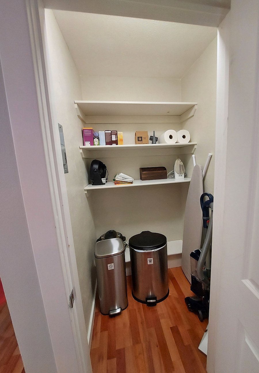 Dedicated storage with recycling, trash, vacuum, ironing board and household essentials.
