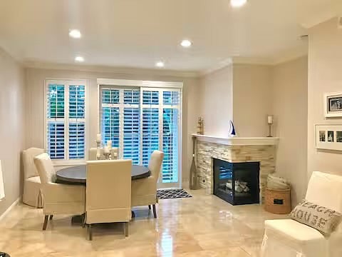 Dining room with gas fireplace overlooking patio. Plantation shutters.