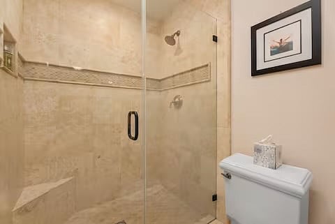 Large walk-in large shower in separate private toilet are with mosaic travertine.