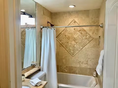 En-suite bath for 2nd bedroom with large soaking tub and shower with mosaic travertine.