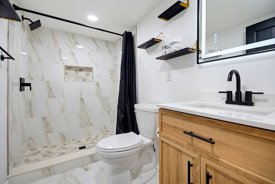 Beautiful tiled bathroom with exposed finishes and floating storage shelves.