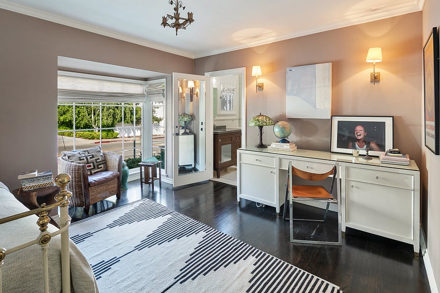 The second bedroom featuring a desk for work, a queen-size bed, adjoining bathroom and view of the street.