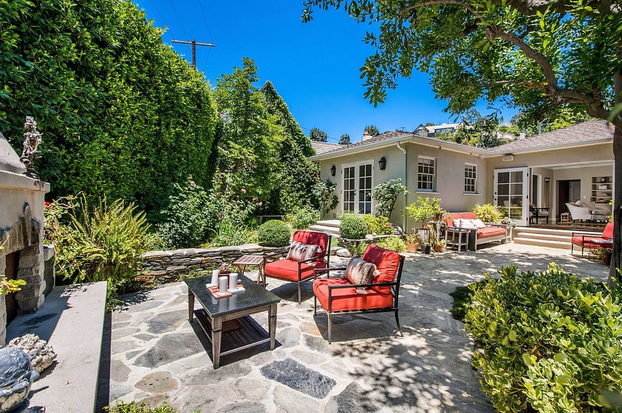 View of the backyard featuring comfortable seating at the outdoor fireplace.
