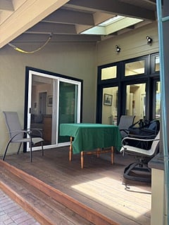 Covered Deck off sliding glass door. Table and cha, and garden view.