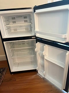 Refrigerator opened to show freezer and main section.