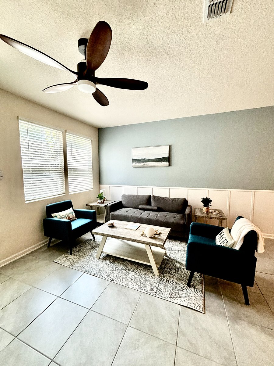 Living room area with sofa, two armchairs, coffee table, rug, and two side tables