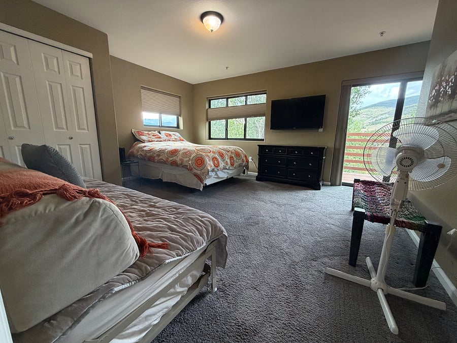 view from hallway into master b/r; trundle bed on left, sliding door to upstairs deck on right. Black out blinds are on both windows and the sliding door