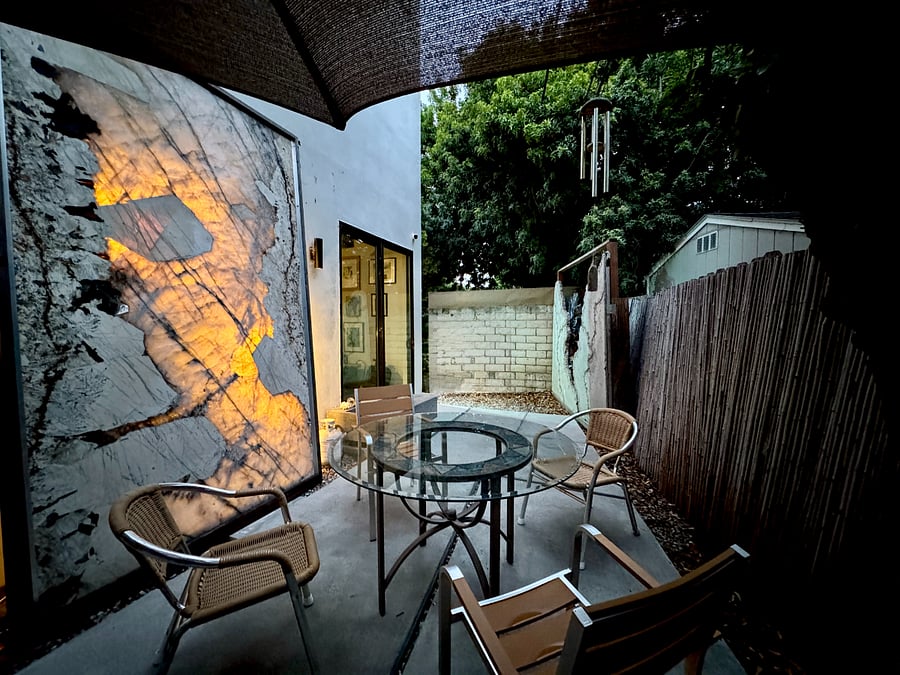 This is a private outdoor space with an illuminated granite slab, a large-scale glass and concrete sculpture adjacent to a BBQ.