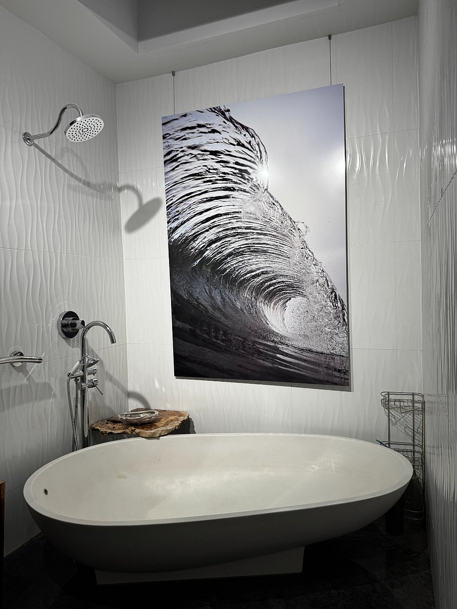 Master bathroom with giant metal wave photo, agape spoon vessel bathtub and custom live edge vanity