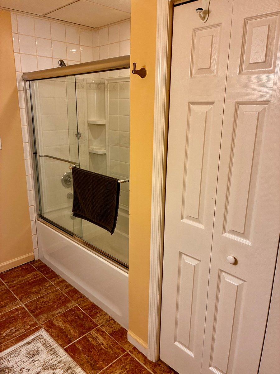 Bathroom with 3 x sets of towels and shower mat, and long rug under the sink vanity.