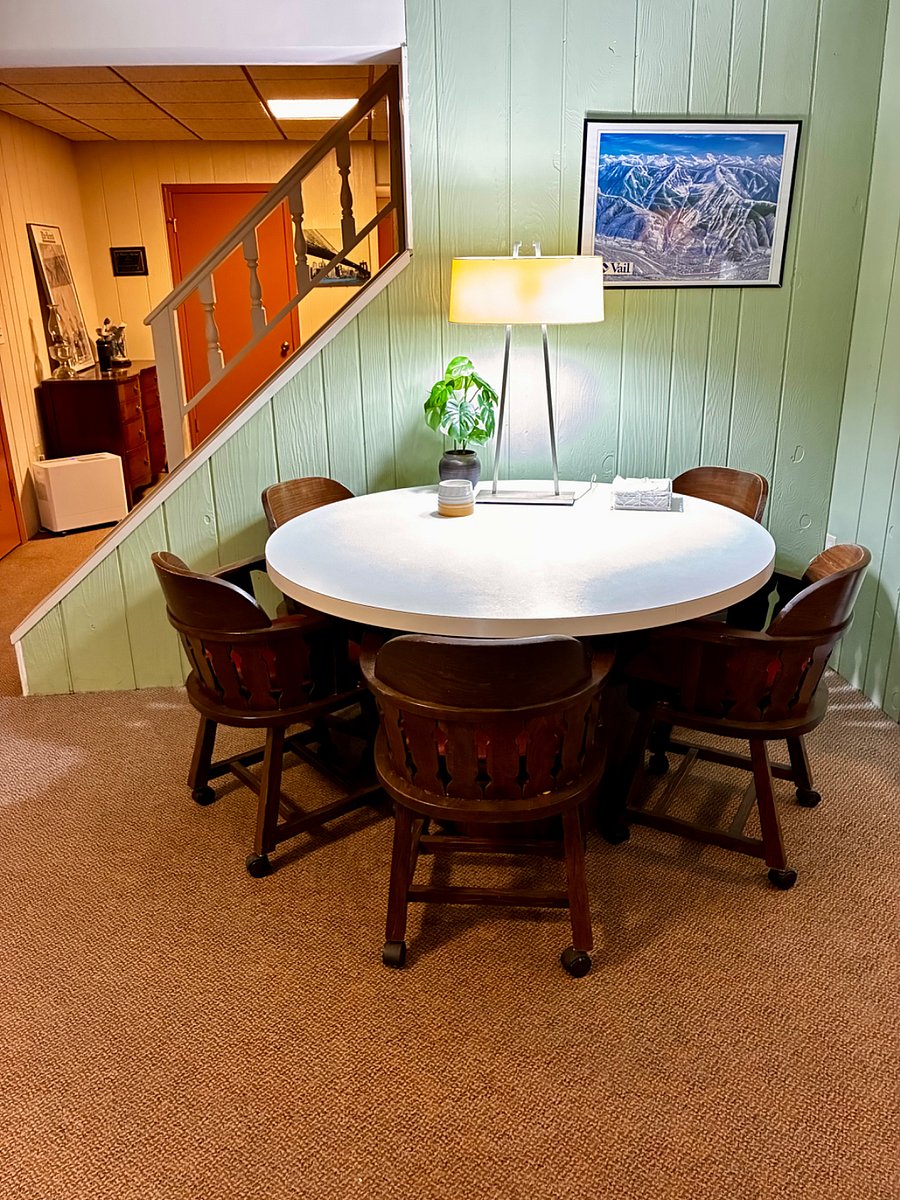 Large round dining table with lamps and 6 x bucket chairs on wheels.
