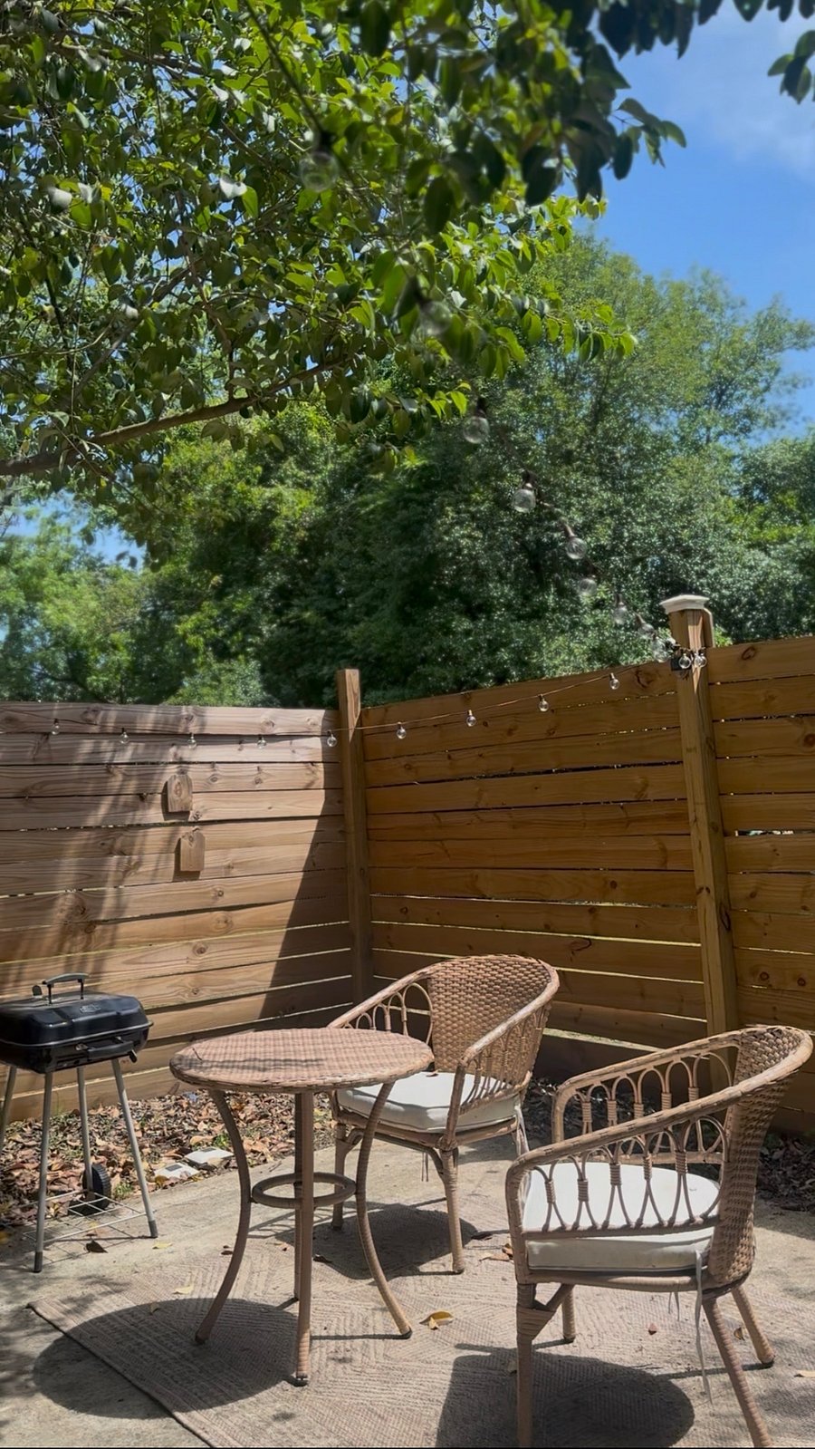Private patio with a charcoal grill and fence gate.