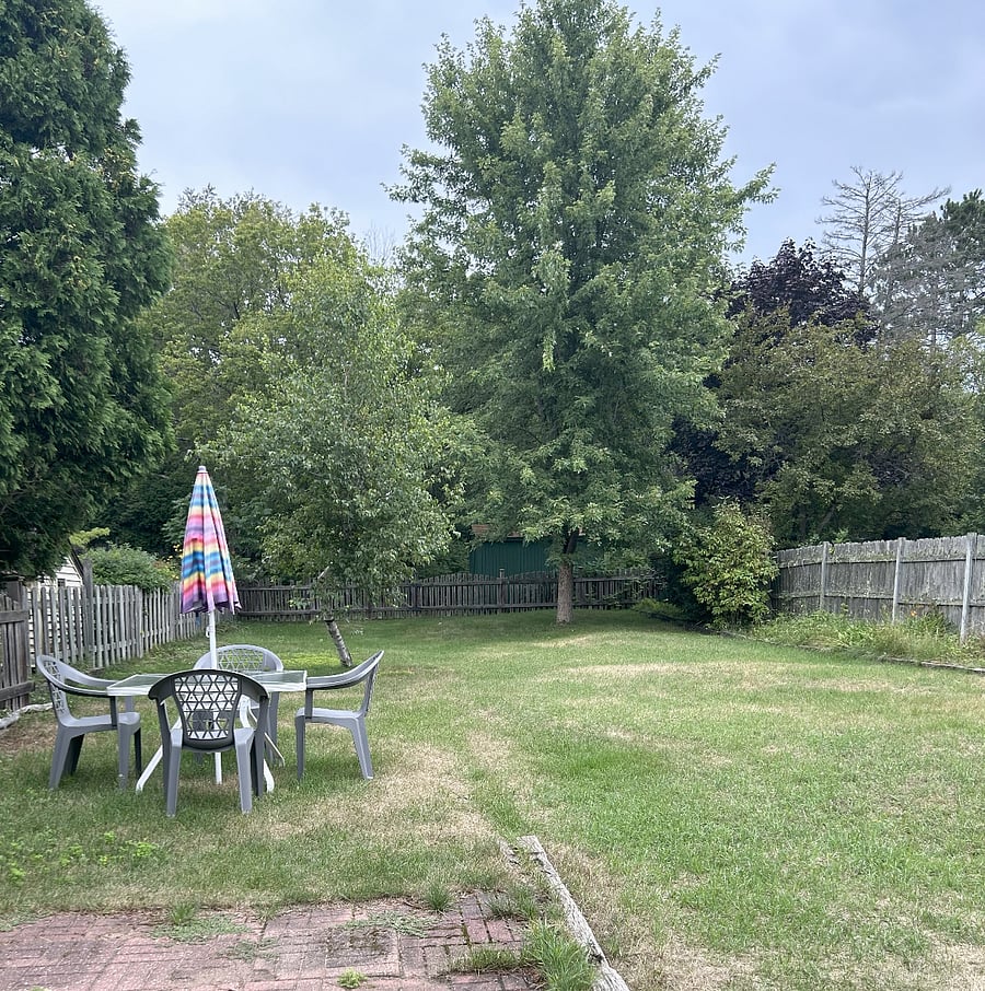 Large enclosed backyard includes some gardens, outdoor table/ seating and gas grill. Path through the woods leads to the sandy shores of Lake Superior.