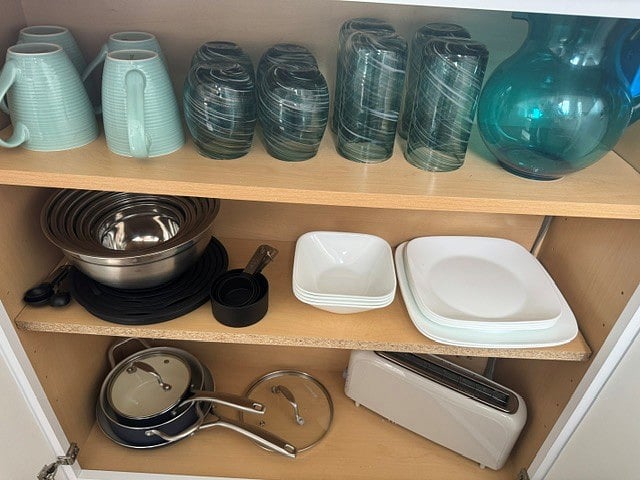 Kitchen stocked with dishes, mixing bowls, pots and pans, bakeware, utensils, toaster, coffee pot and kitchen linens