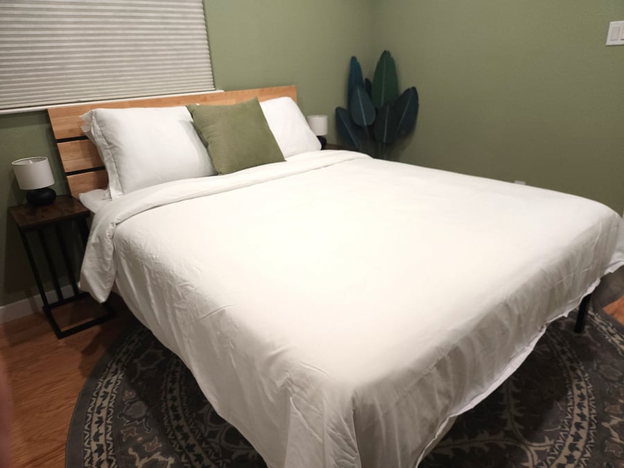 Queen bed with modern bed frame, bed side tables, and reading lamps.