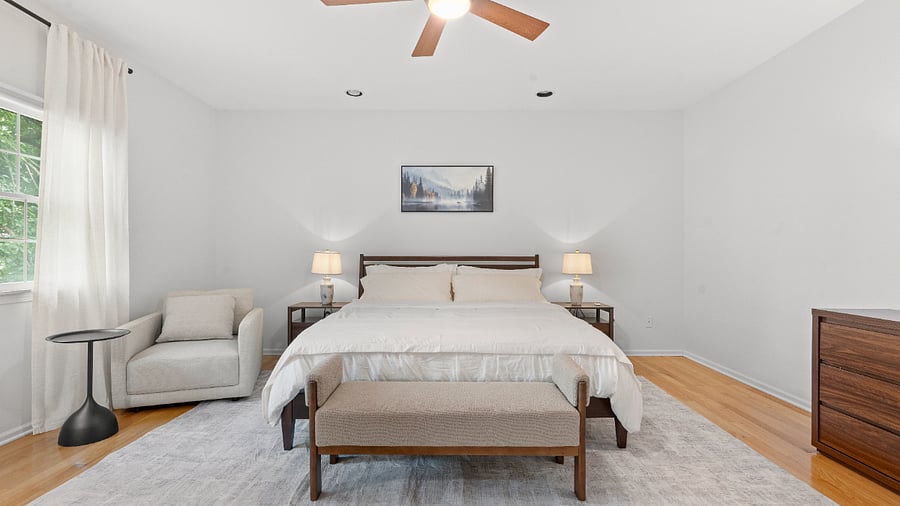 Primary bedroom with a comfortable reading chair, generous closet space, and private ensuite bathroom.