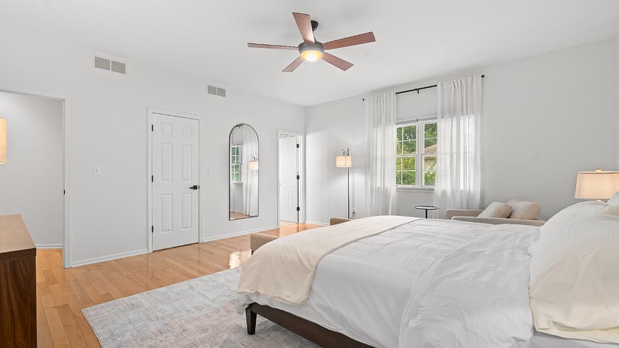 Primary bedroom with a comfortable reading chair, generous closet space, and private ensuite bathroom.