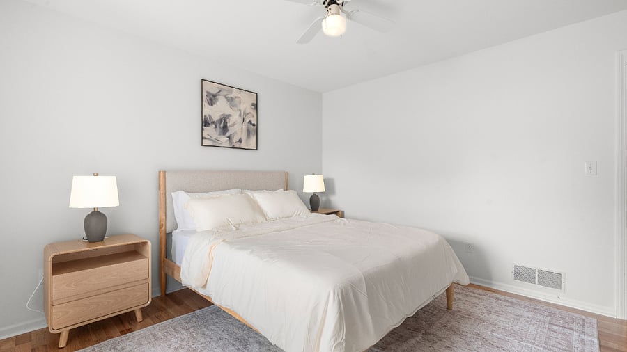 Inviting upper-level queen bedroom with clean linens, comfortable furnishings, and a dedicated writing desk.