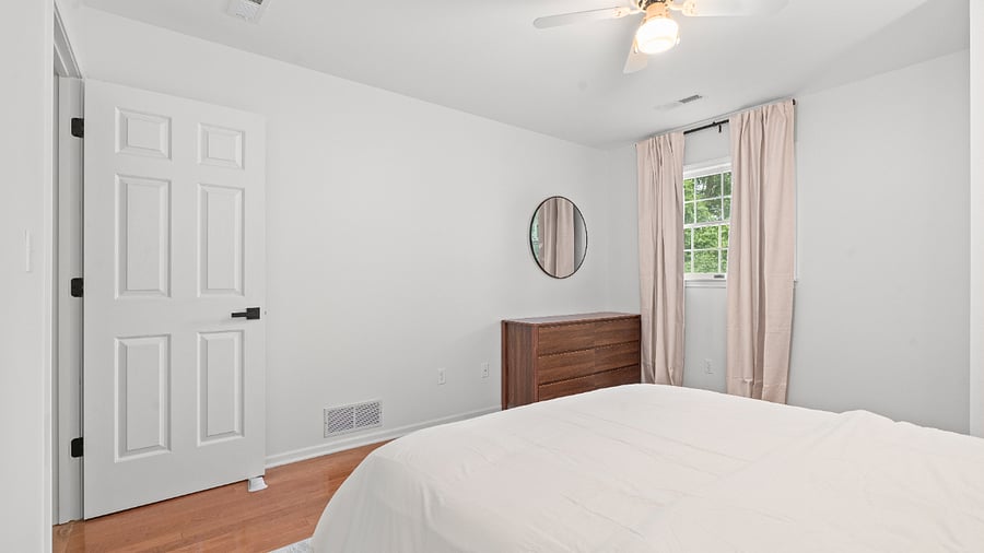 Comfortable upper-level bedroom with a queen bed, dresser, ceiling fan, and closet storage.